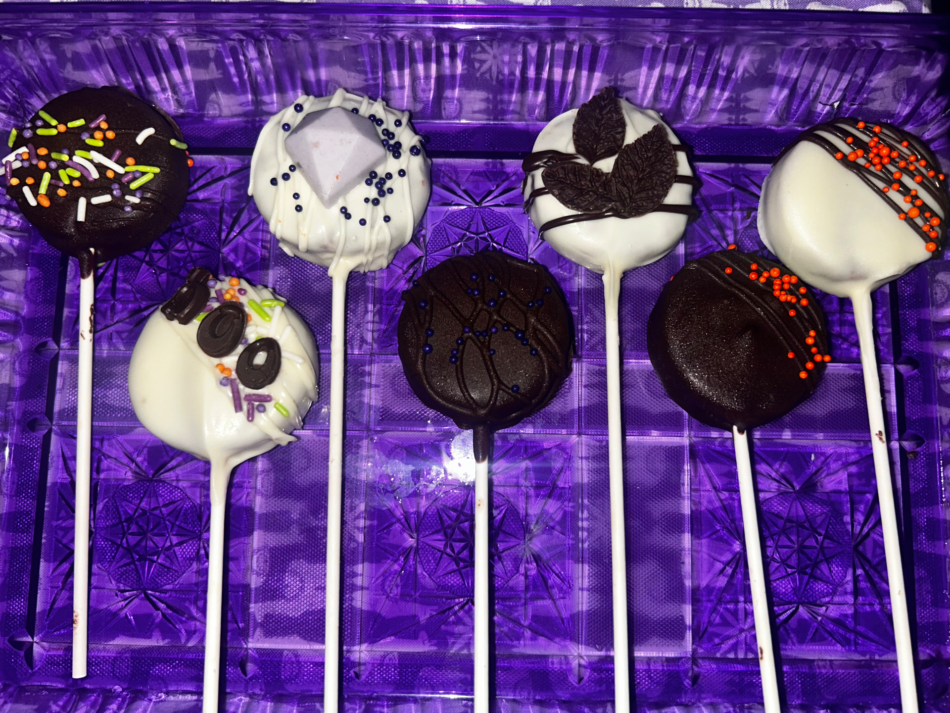 Assorted cake pops with sprinkles, chocolate leaves and a diamond topper